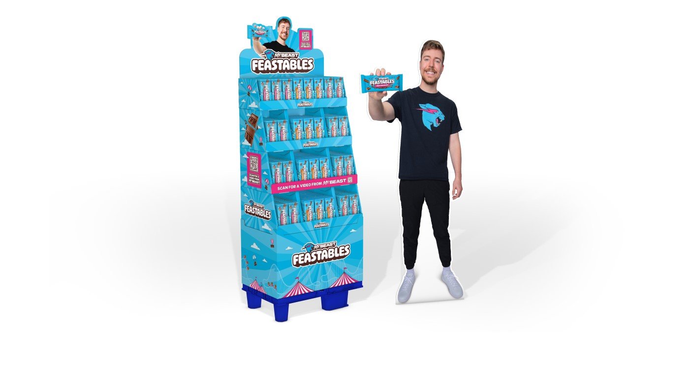 MrBeast präsentiert seine Schokolade nben einem blauen MrBeast Display gefüllt mit Schokolade.